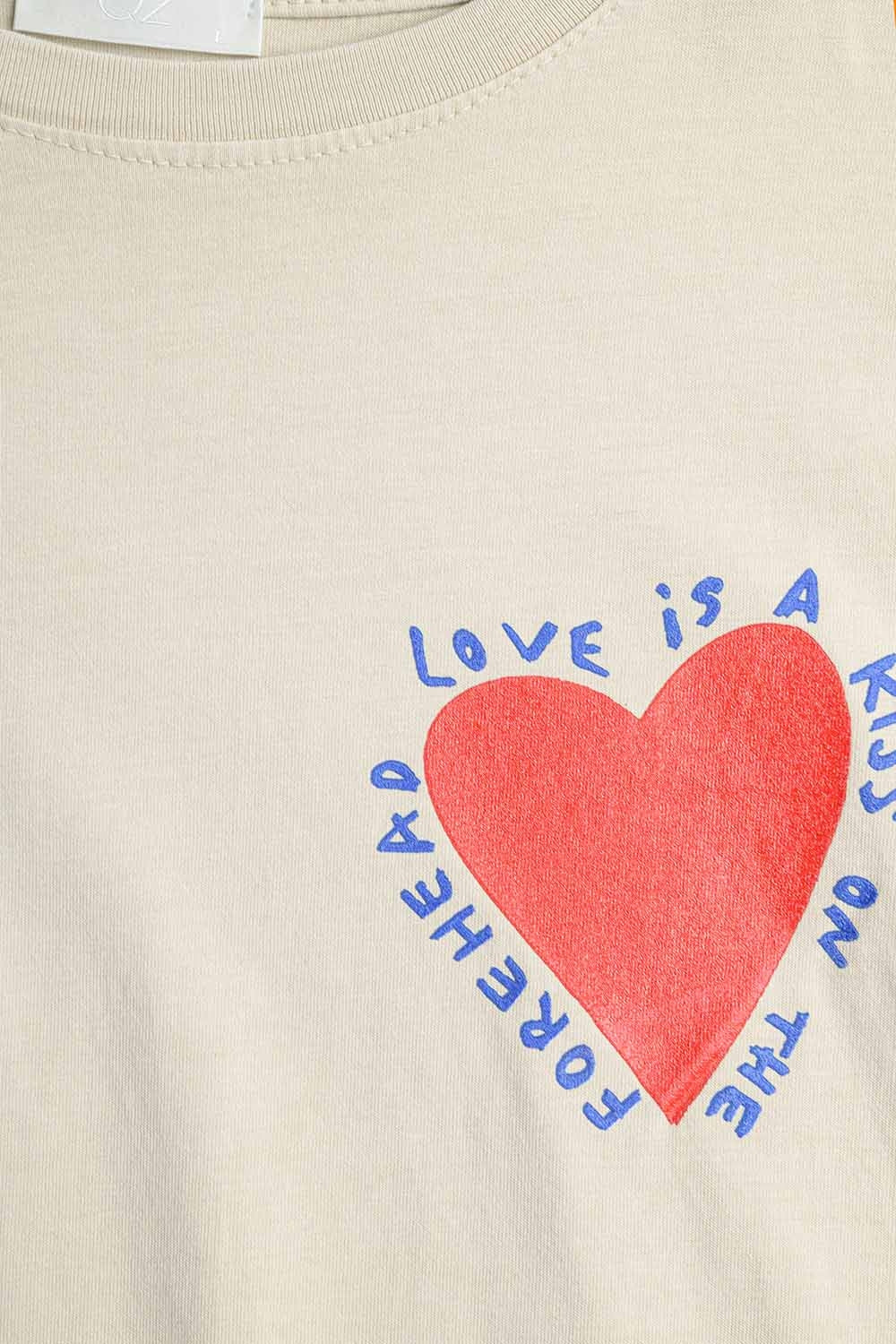 T-shirt beige rilassata con disegno di un cuore sul davanti e sul dietro