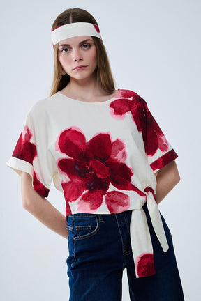 Camicetta cropped beige con stampa floreale tropicale in rosso legata in vita